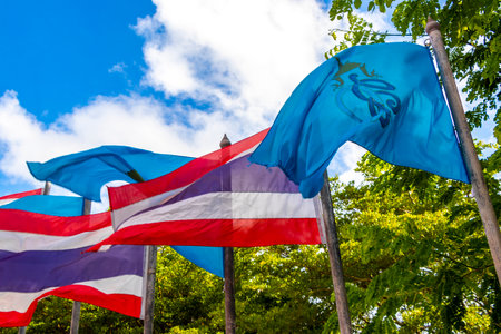Thai flag blowing in the wind in tropical nature and blue sky in Patong Beach Kathu District Phuket Island Province Southern Thailand in Southeast Asia.の写真素材