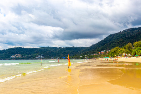 Kathu Phuket Thailand October 17, 2025 Patong Beach bay sea coast panorama view with promenade tourists people turquoise blue clear water waves and green mountains and palm trees in Patong Thailand.の写真素材