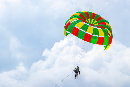 Kathu Phuket Thailand October 17, 2025 Patong Beach bay sea coast panorama view with people tourism and parasailing parachute sport activity water waves mountains and clouds in Phuket Thailand.の写真素材