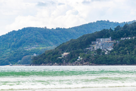 Patong Beach bay sea coast panorama view with turquoise blue clear water waves and green mountains hills and palm trees in Patong Beach Kathu District Phuket Island Province Southern Thailand.の写真素材