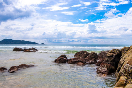 Amazing rocky beach tropical landscape panorama view with turquoise blue water waves and rocks in Patong Beach Kathu District Phuket Island Province Southern Thailand in Southeast Asia.の写真素材