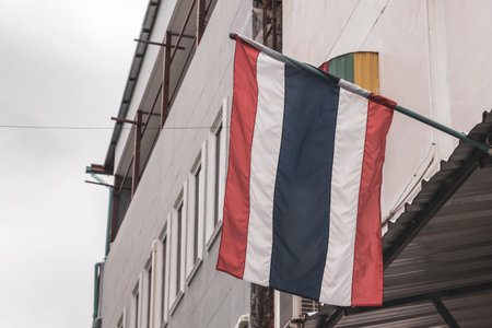 Thai flag blowing in the wind in the city and blue sky in Patong Beach Phuket Island Thailand in Southeast Asia.の写真素材