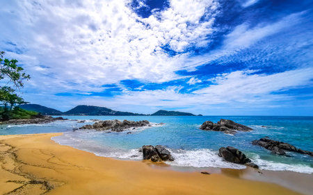 Amazing rocky Kalim Beach tropical landscape panorama view with blue sky turquoise water waves palm trees and rocks in Patong Beach Kathu Phuket Island Province Southern Thailand in Southeast Asia.の写真素材