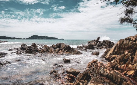 Amazing rocky Kalim Beach tropical landscape panorama view with blue sky turquoise water waves and rocks in Patong Beach Kathu District Phuket Island Province Southern Thailand in Southeast Asia.の写真素材