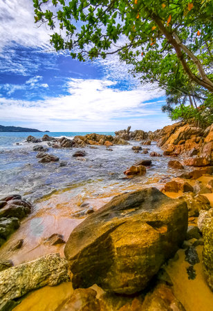 Amazing rocky Kalim Beach tropical landscape panorama view with blue sky turquoise water waves palm trees and rocks in Patong Beach Kathu Phuket Island Province Southern Thailand in Southeast Asia.の写真素材
