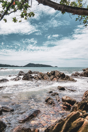 Amazing rocky Kalim Beach tropical landscape panorama view with blue sky turquoise water waves palm trees and rocks in Patong Beach Kathu Phuket Island Province Southern Thailand in Southeast Asia.の写真素材