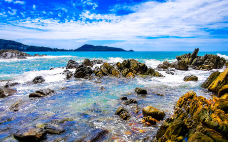 Amazing rocky Kalim Beach tropical landscape panorama view with blue sky turquoise water waves and rocks in Patong Beach Kathu District Phuket Island Province Southern Thailand in Southeast Asia.の写真素材