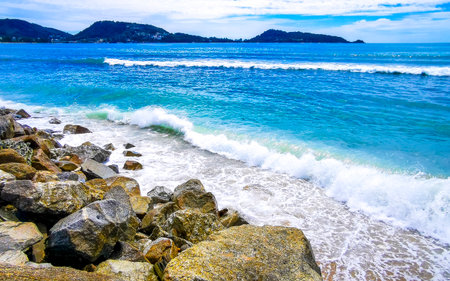 Amazing rocky Kalim Beach tropical landscape panorama view with blue sky turquoise water waves and rocks in Patong Beach Kathu District Phuket Island Province Southern Thailand in Southeast Asia.の写真素材