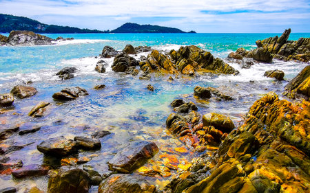 Amazing rocky Kalim Beach tropical landscape panorama view with blue sky turquoise water waves and rocks in Patong Beach Kathu District Phuket Island Province Southern Thailand in Southeast Asia.の写真素材