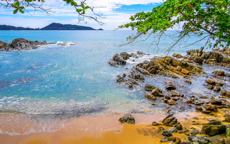 Amazing rocky Kalim Beach tropical landscape panorama view with blue sky turquoise water waves palm trees and rocks in Patong Beach Kathu Phuket Island Province Southern Thailand in Southeast Asia.の写真素材