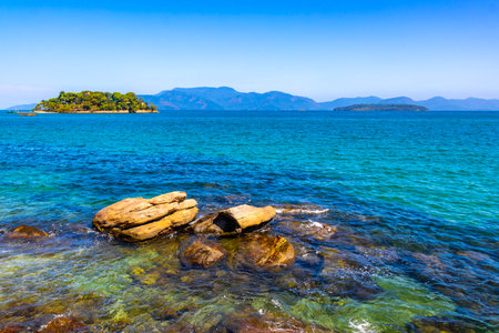 Panorama of tropical islands nature coast beach with turquoise green and clear water rock rocks boulders boulder and blue sky in Angra dos Reis State of Rio de Janeiro Brazil.の写真素材