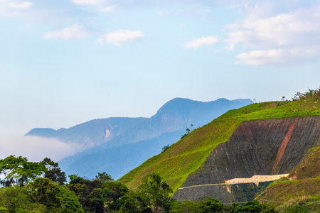 Tropical mountain mountains hill hills with jungle forest trees plants clouds and blue sky.の写真素材