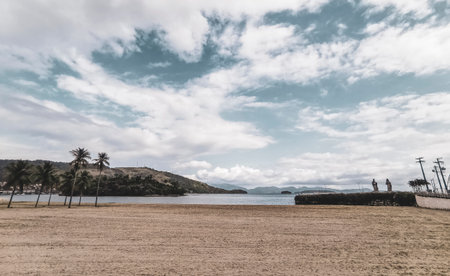 Panorama of tropical Anil Beach with coastal shore seascape turquoise green clear water pier port harbor with boats blue sky and palm trees in Angra dos Reis State of Rio de Janeiro Brazil.の写真素材