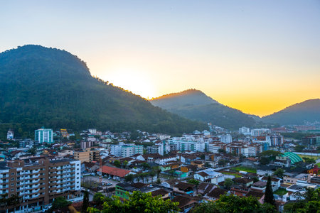 Beautiful golden colorful sunrise sunset behind the tropical mountain hill with city town panorama view.の写真素材