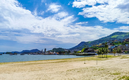 Panorama of tropical Anil Beach with coastal shore seascape turquoise green clear water pier port harbor with boats blue sky and palm trees in Angra dos Reis State of Rio de Janeiro.の写真素材