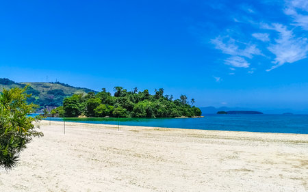 Panorama of tropical Anil Beach with coastal shore seascape turquoise green clear water pier port harbor with boats blue sky and palm trees in Angra dos Reis State of Rio de Janeiro Brazil.の写真素材