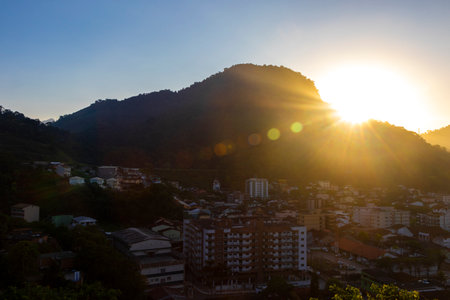 Beautiful golden colorful sunrise sunset behind the tropical mountain with city town panorama view.の写真素材