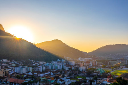 Beautiful golden colorful sunrise sunset behind the tropical mountain with city town panorama view in Angra dos Reis, State of Rio de Janeiro, Brazil.の写真素材