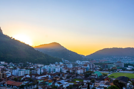 Beautiful golden colorful sunrise sunset behind the tropical mountain hill with city town panorama view in Angra dos Reis State of Rio de Janeiro Brazil.の写真素材