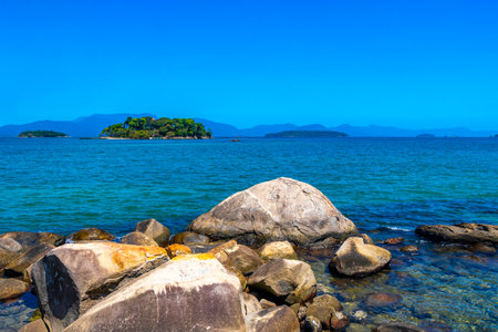 Panorama of tropical islands nature coast beach with turquoise green and clear water rock rocks boulders boulder and blue sky in Angra dos Reis State of Rio de Janeiro Brazil.の写真素材