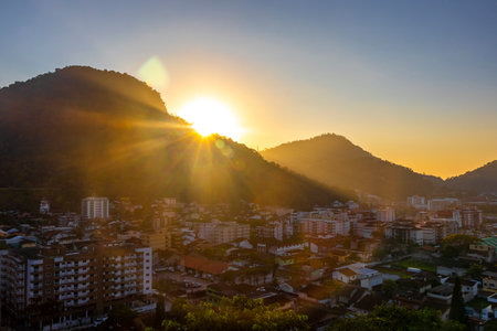 Beautiful golden colorful sunrise sunset behind the tropical mountain mountains hill hills with city town panorama view in Angra dos Reis Brazil.の写真素材