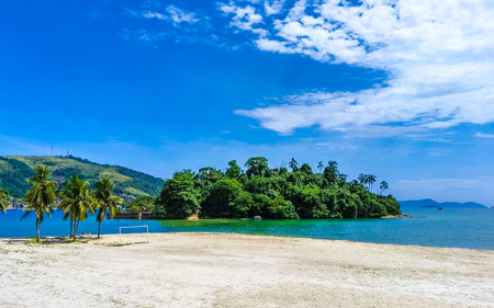 Panorama of tropical Anil Beach with coastal shore seascape turquoise green clear water pier port harbor with boats blue sky and palm trees in Angra dos Reis State of Rio de Janeiro Brazil.の写真素材