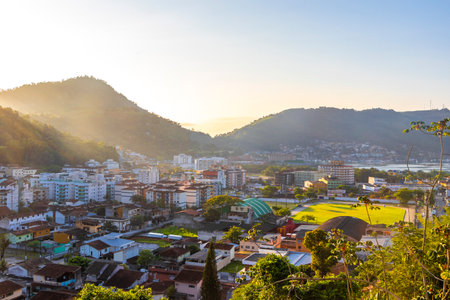 Beautiful golden colorful sunrise sunset behind the tropical mountain with city town panorama view in Angra dos Reis, State of Rio de Janeiro, Brazil.の写真素材
