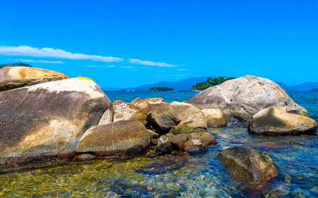 Panorama of tropical islands nature coast beach with turquoise green and clear water rock rocks boulders boulder and blue sky in Angra dos Reis State of Rio de Janeiro Brazil.の写真素材