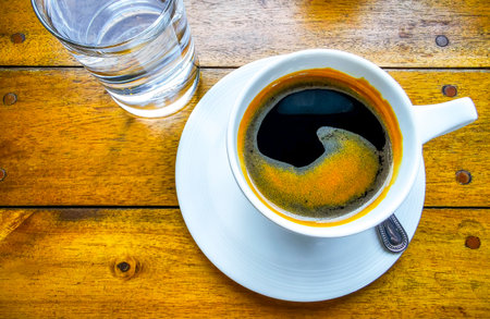 Glass cup of americano black coffee with spoon and plate on table food and drink in the restaurant cafe in Patong Beach Kathu District Phuket Island Province Southern Thailand in Southeast Asia.の写真素材