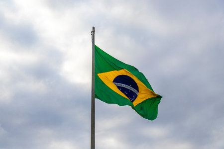 Brazilian flag waving in the wind with cloudy dark gray sky in the background in Rio de Janeiro State of Rio de Janeiro Brazil.の写真素材