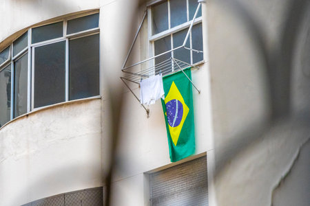 Brazilian flag waving in the wind with cloudy dark gray sky in the background in Rio de Janeiro Brazil.の写真素材