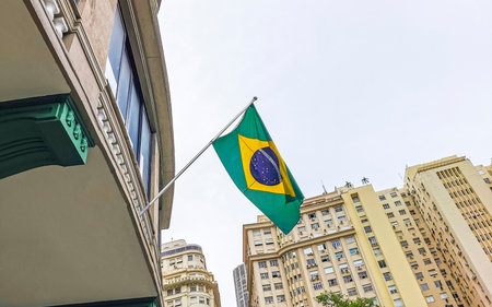 Brazilian flag waving in the wind with cloudy dark gray sky in the background in Rio de Janeiro Brazil.の写真素材