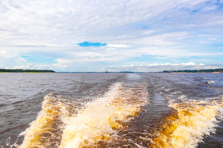 Meeting of waters blackwater of Rio Negro and whitewater of Amazon River boat trip tour with tropical jungle rainforest and blue cloudy sky in Iranduba Manaus State of Amazonas Brazil.の写真素材