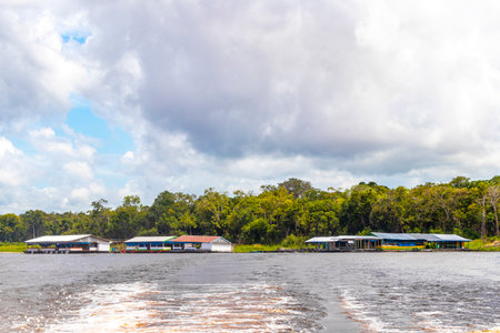 Village huts and houses on stilts in the water tropical jungle rainforest and blue cloudy sky at the...