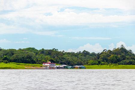 Village huts and houses on stilts in the water tropical jungle rainforest and blue cloudy sky at the...