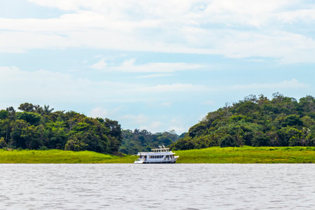 Meeting of waters blackwater of Rio Negro and whitewater of Amazon River boat trip tour with tropical jungle rainforest and blue cloudy sky in Iranduba Manaus State of Amazonas Brazil.の写真素材