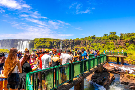 Foz do Iguacu Parana Brazil December 26, 2020 Iguazu Falls waterfall fall waterfalls cascades in tropical nature panorama with wooden trail people blue sky turquoise green water Brazil and Argentina.のeditorial素材
