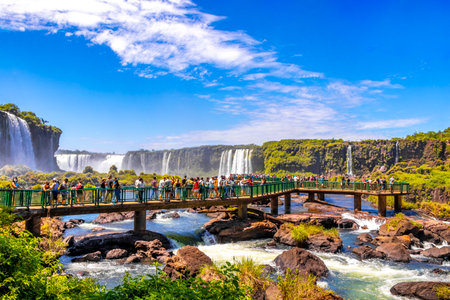 Foz do Iguacu Parana Brazil December 26, 2020 Iguazu Falls waterfall fall waterfalls cascades in tropical nature panorama with wooden trail people blue sky turquoise green water Brazil and Argentina.のeditorial素材