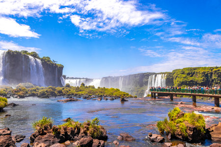 Foz do Iguacu Parana Brazil December 26, 2020 Iguazu Falls waterfall fall waterfalls cascades in tropical nature panorama with wooden trail people blue sky turquoise green water Brazil and Argentina.のeditorial素材