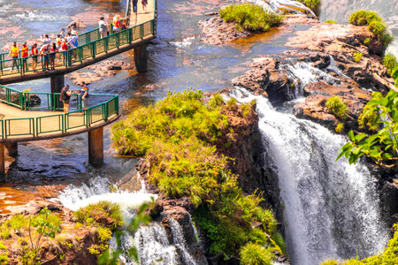 Foz do Iguacu Parana Brazil December 26, 2020 Iguazu Falls waterfall fall waterfalls cascades in tropical nature panorama with wooden trail people blue sky turquoise green water Brazil and Argentina.のeditorial素材