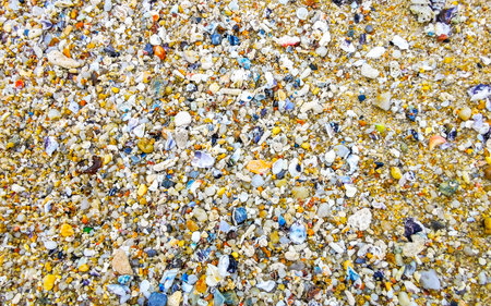 Beach sand with pebbles stones rocks colorful shells mussels and turquoise blue clear water texture pattern in Patong Kalim Beach Kathu District Phuket Island Province Southern Thailand in Southeast Asia.の写真素材