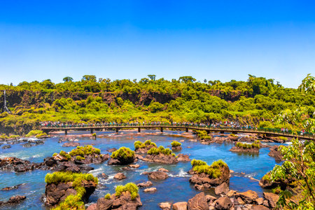 Foz do Iguacu Parana Brazil December 26, 2020 Iguazu Falls waterfall fall waterfalls cascades in tropical nature panorama with wooden trail people blue sky turquoise green water Brazil and Argentina.のeditorial素材