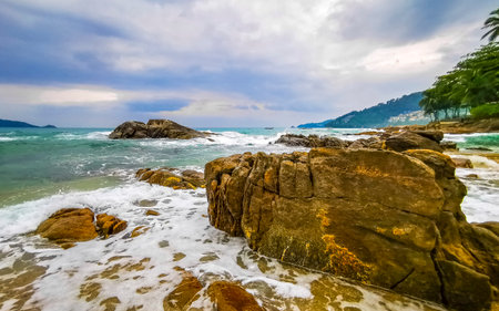 Amazing rocky Kalim Beach tropical landscape panorama view with blue sky turquoise water waves palm trees and rocks in Patong Beach Kathu Phuket Island Province Southern Thailand in Southeast Asia.の写真素材
