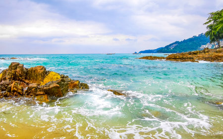 Amazing rocky Kalim Beach tropical landscape panorama view with blue sky turquoise water waves and rocks in Patong Beach Kathu District Phuket Island Province Southern Thailand in Southeast Asia.の写真素材