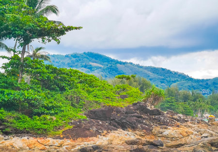Amazing rocky Kalim Beach tropical landscape panorama view with blue sky turquoise water waves palm trees and rocks in Patong Beach Kathu Phuket Island Province Southern Thailand in Southeast Asia.の写真素材