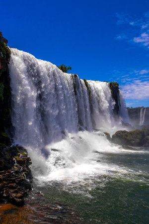 Foz do Iguacu Iguazu Falls waterfall fall waterfalls cascade cascades in tropical nature rainforest panorama view with blue sky and turquoise green water in Parana Brazil and Misiones Argentina.の写真素材