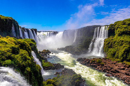 Foz do Iguacu Iguazu Falls waterfall fall waterfalls cascade cascades in tropical nature rainforest panorama view with blue sky and turquoise green water in Parana Brazil and Misiones Argentina.の写真素材
