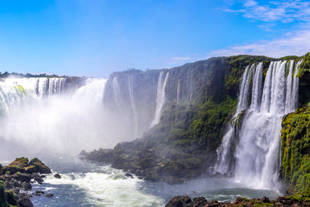 Foz do Iguacu Iguazu Falls waterfall fall waterfalls cascade cascades in tropical nature rainforest panorama view with blue sky and turquoise green water in Parana Brazil and Misiones Argentina.の写真素材