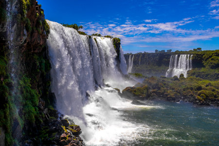 Foz do Iguacu Iguazu Falls waterfall fall waterfalls cascade cascades in tropical nature rainforest panorama view with blue sky and turquoise green water in Parana Brazil and Misiones Argentina.の写真素材