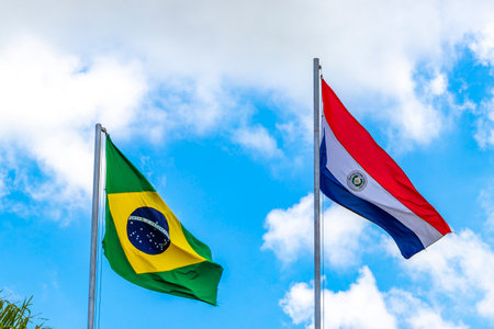 Brazilian and Paraguayan flag waving in the wind with blue sky in the background.の写真素材